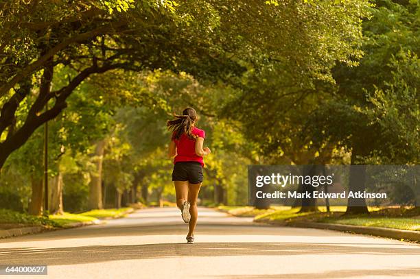 caucasian woman jogging on neighborhood street - suburb park stock pictures, royalty-free photos & images