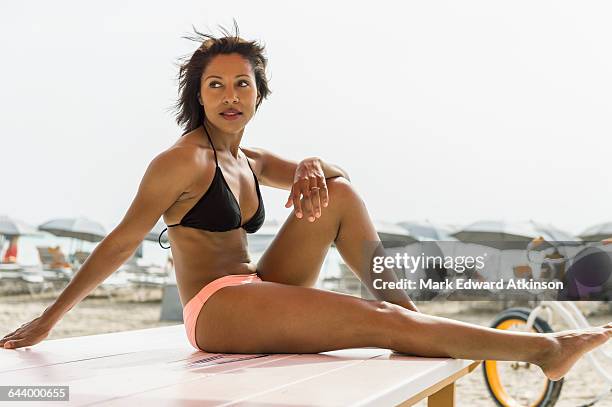 african american woman sitting on deck chair on beach - african american women in the wind stock pictures, royalty-free photos & images