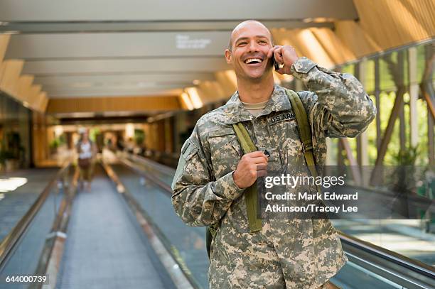 caucasian soldier talking on cell phone in airport - army soldier smiling stock pictures, royalty-free photos & images