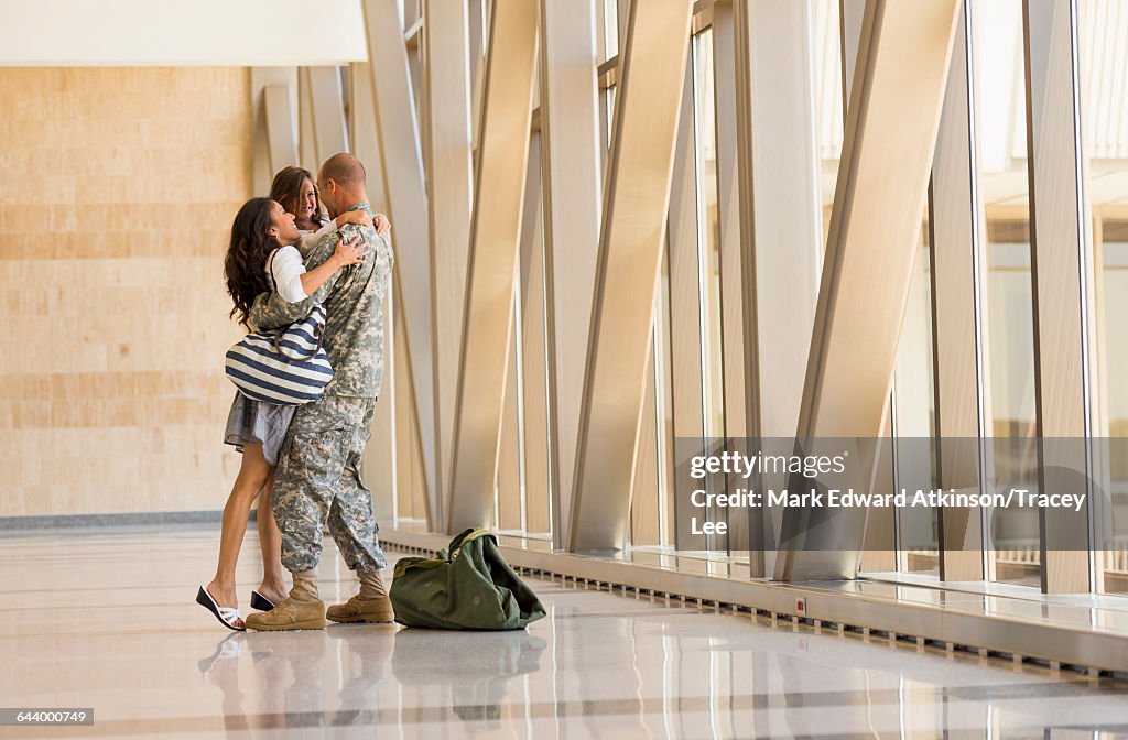 Returning soldier greeting family in airport