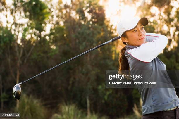 mixed race woman playing golf on golf course - swinging golf club stock pictures, royalty-free photos & images