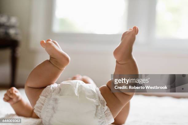 mixed race baby girl laying on floor - baby diaper stockfoto's en -beelden