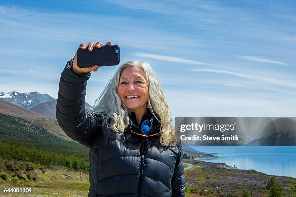 caucasian woman photographing remote landscape - new zealand travel stock pictures, royalty-free photos & images