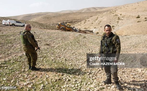 Israeli security forces stand guard by a tractor that became stuck during the demolition of a Bedouin water well in Yatta, south of the flashpoint...