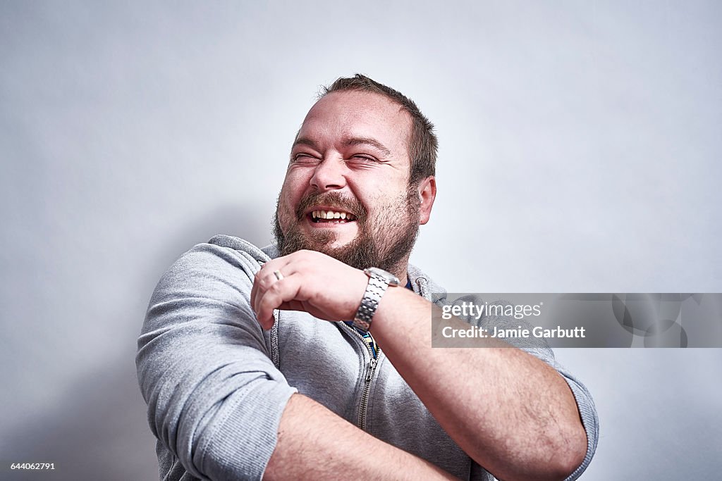 Bearded British male laughing hysterically