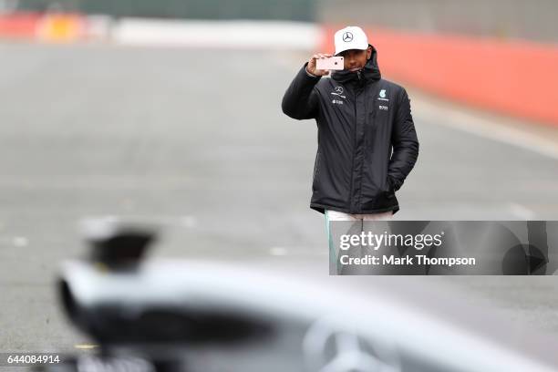 Lewis Hamilton of Great Britain and Mercedes GP uses his mobile phone as he walks out for the launch of the Mercedes formula one team's 2017 car, the...