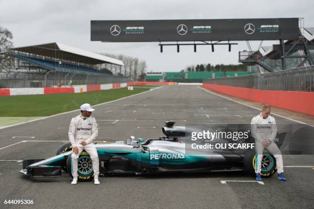 Mercedes AMG Petronas Formula One drivers Britain's Lewis Hamilton and Finland's Valtteri Bottas pose by the new 2017 season Mercedes W08 EQ Power+...