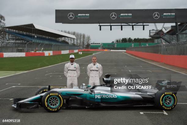 Mercedes AMG Petronas Formula One drivers Britain's Lewis Hamilton and Finland's Valtteri Bottas pose by the new 2017 season Mercedes W08 EQ Power+...