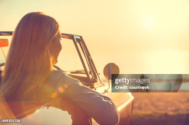 giovane donna in macchina in spiaggia. - old fashioned australian beach foto e immagini stock