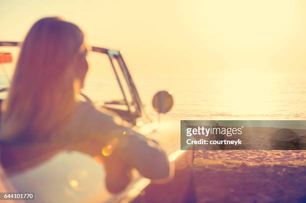 giovane donna in macchina in spiaggia. - old fashioned australian beach foto e immagini stock