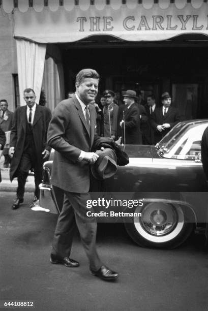 President Kennedy, despite the cold weather, carries his hat and coat in hand as he leaves the Carlyle Hotel December 15th, en route to LaGuardia...