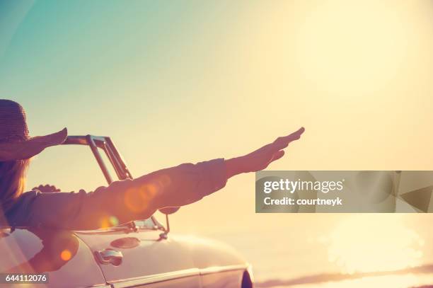 woman with her hand out of the car window. - convertible car stock pictures, royalty-free photos & images