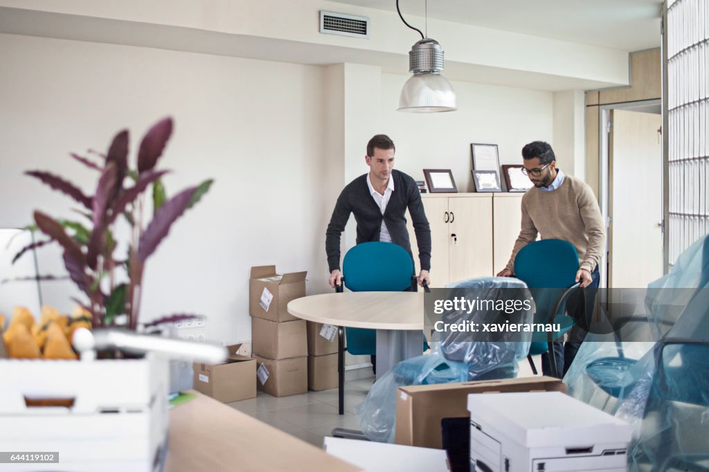 Businessmen arranging chairs in new office