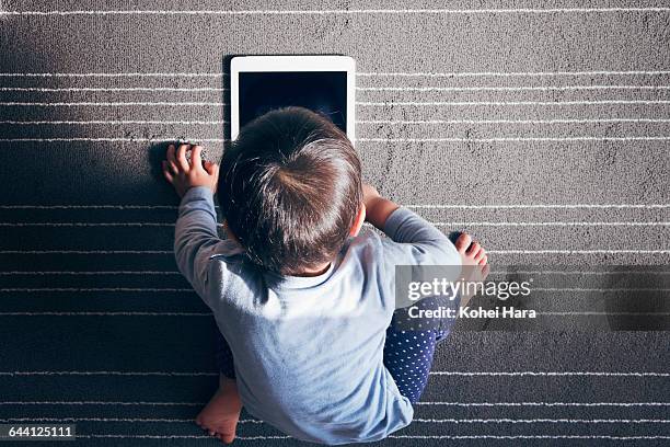 a boy using a tablet pc on carpet - boy using ipad imagens e fotografias de stock