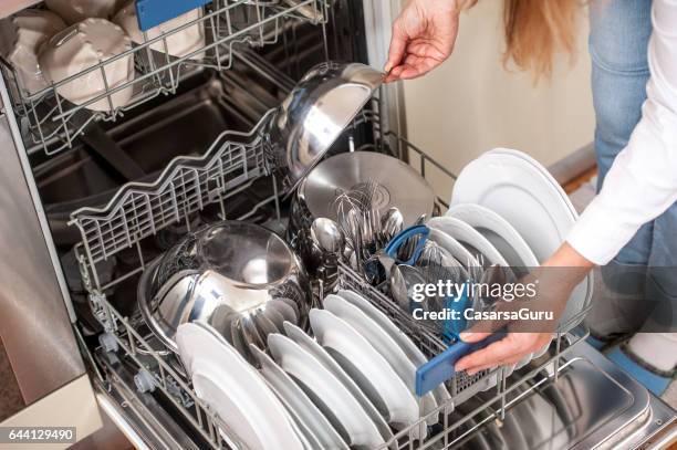 erwachsene frau entladen geschirrspüler in der küche - dishwasher stock-fotos und bilder