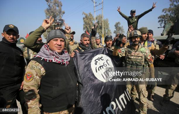 Iraqi forces flash the sign for victory while holding an Islamic State group flag on February 23 as they enter Mosul airport on the southern edge of...