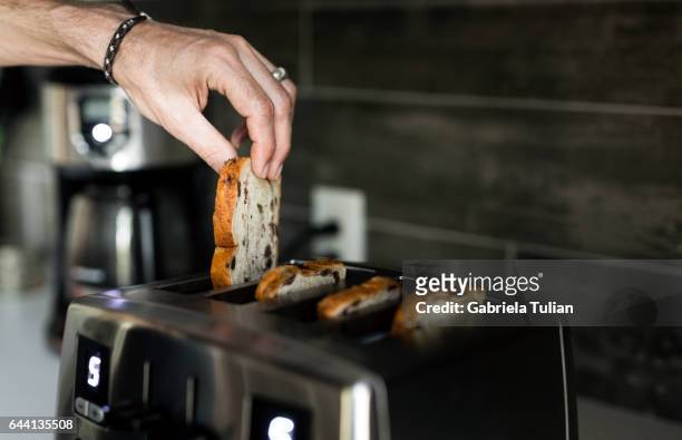 male hand taking baked toast out of toaster - toaster stockfoto's en -beelden