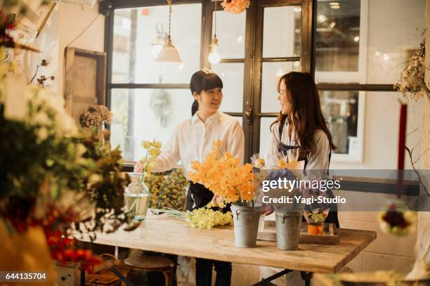 two female workers working in green shop. - asia lady selling flower stock pictures, royalty-free photos & images