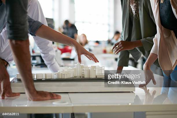 co-workers gathered around architectural model - architect stock pictures, royalty-free photos & images