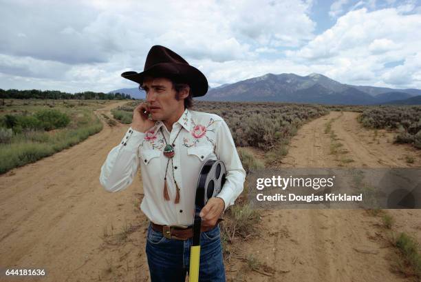 Dennis Hopper stands at the cross of two dirt roads in the New Mexico desert.