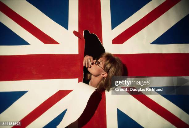 Actress Vanessa Redgrave smokes a cigarette through a rip in a Union Jack.