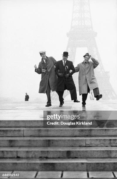 Photographer Douglas Kirkland and journalists Art Buchwald and Jack Star kick up their heels together in front of the Eiffel Tower on a foggy day.