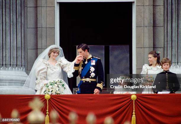 Newlyweds Princess Diana and Prince Charles stand before onlookers at the balcony at Buckingham Palace just after their wedding, attended by young...