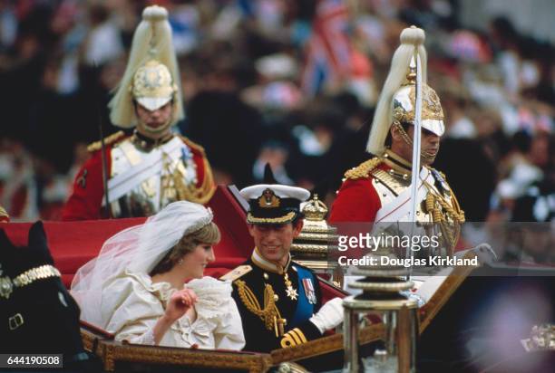 Prince Charles and Princess Diana, just married, ride from St. Paul's Cathedral to Buckingham Palace in an open carriage, escorted by guardsmen and...