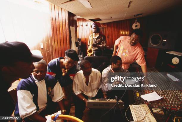 At a recording session in Dakar, African musicians prepare to work together. Seated are Papa Wemba; Lourdes Van-Dunem looks over his shoulder. An...