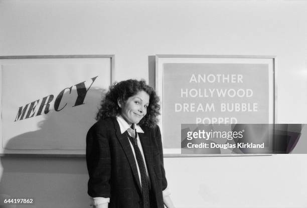 Portrait of movie actress Lois Chiles standing next to a framed poster with Another Hollywood dream bubble popped written on it in 1983. Chiles was a...