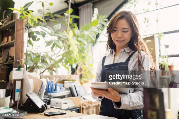 jonge vrouwelijke werknemer die werkt in de bloemenwinkel. - asia lady selling flower stockfoto's en -beelden