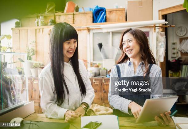 zwei weibliche arbeitnehmer arbeitet in grün-shop. - nur japaner stock-fotos und bilder