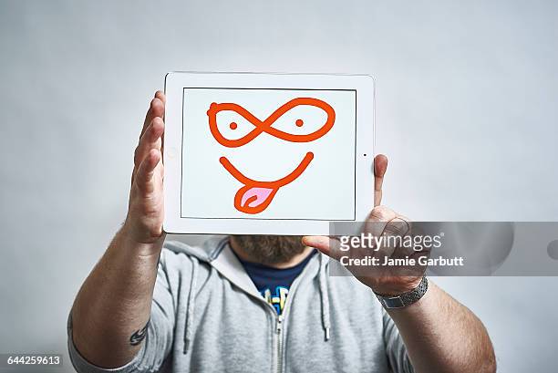 male holding a tablet with illustrated face on it - newnaivetytrend ストックフォトと画像