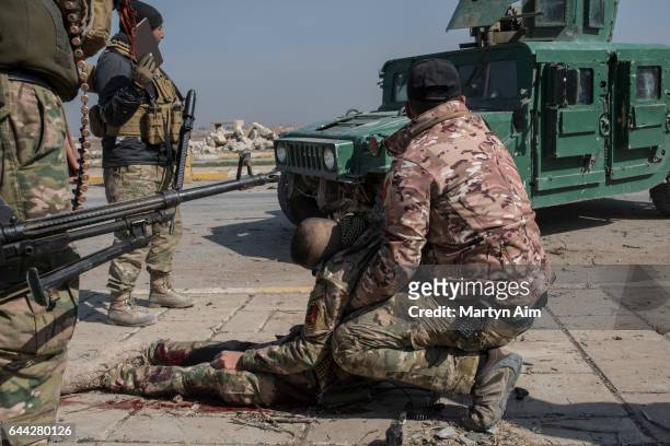 An injured Iraqi Emergency Response Division soldier hit by a mortar is held by another officer as they wait for medics to arrive at the Islamic...