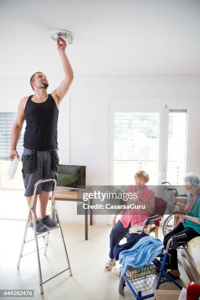 electrician changing light bulb in the elderly center - changing lightbulb stock pictures, royalty-free photos & images