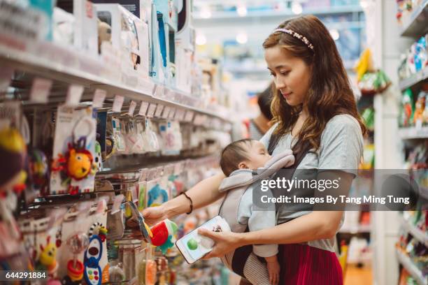 pretty young mom shopping for baby products with her baby in department store. - babyausrüstung stock-fotos und bilder