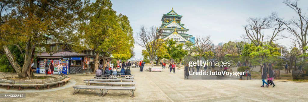 Turistas de Japón en las zonas verdes alrededor de panorama del castillo de Osaka