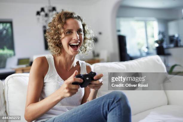 happy woman playing video game at home - sleeveless ストックフォトと画像