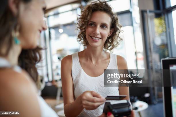 woman in a shop paying with credit card - credit card stock-fotos und bilder