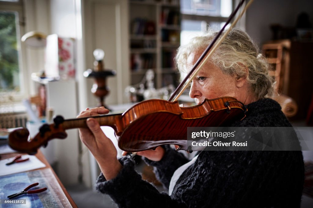 Senior woman playing violin at home