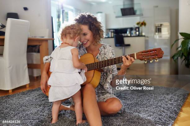 mother with baby girl playing guitar at home - beautiful blonde babes 個照片及圖片檔