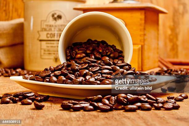 Eine umgekippte Kaffeetasse mit Kaffeebohnen |An overturned coffee cup with coffee beans|