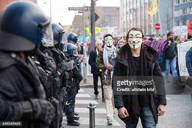 Protesters of the Blockupy anti-capitalist movement with anonymous masks and police officers in a demonstration against austerity and capitalism on...