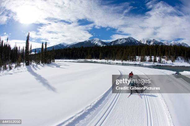 eine frau führt einen mann auf einem langlauf skating-ski in british columbia, kanada. - langlaufski stock-fotos und bilder