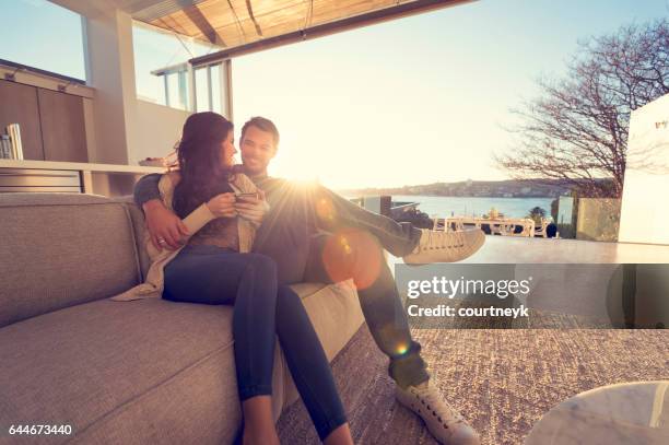 couple on the sofa at sunrise. - luxury home stock pictures, royalty-free photos & images