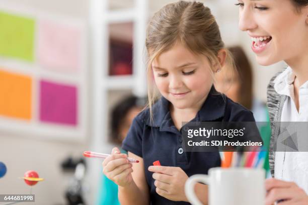 happy teacher with elementary student in art class - kid holding crayons stock pictures, royalty-free photos & images