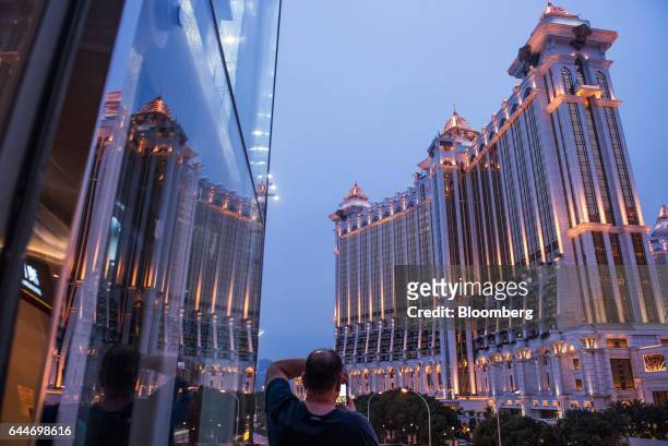 Man uses a smartphone takes a photograph of the Galaxy Macau Phase 2 casino and hotel, developed by Galaxy Entertainment Group Ltd., in Macau, China,...