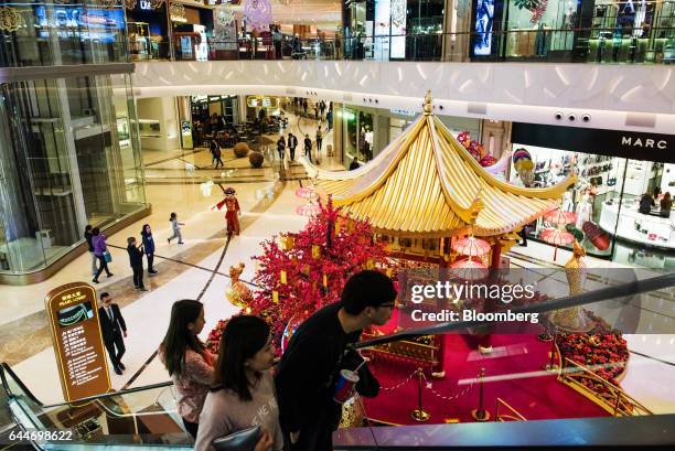 Visitors ride an escalator past stores in the Pearl Lobby of the Promenade Shops shopping area at the Galaxy Macau Phase 2 casino and hotel,...