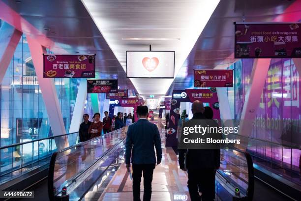 Visitors walk through an overpass connecting Broadway Macau and the Galaxy Macau Phase 2 casino and hotel, both developed by Galaxy Entertainment...