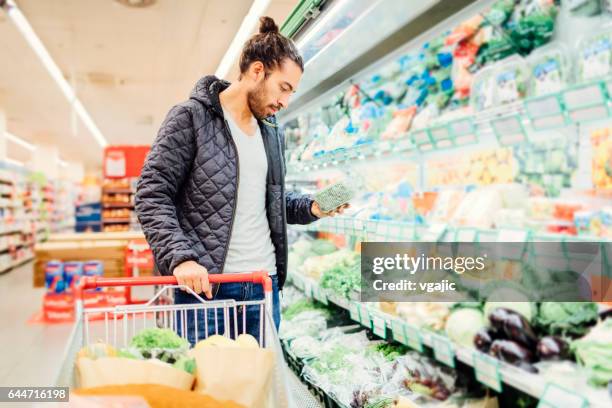 jongeman boodschappen winkelen - groene salade stockfoto's en -beelden